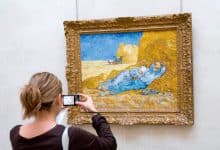 ومضات الكاميرا - إامرأة تلتقط صورة للوحة فنية في المتحف