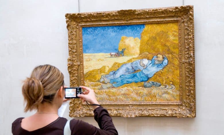 ومضات الكاميرا - إامرأة تلتقط صورة للوحة فنية في المتحف