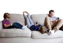 قصر النظر - ثلاث أطفال يجلسون على الأريكة مع هواتفهم الذكية